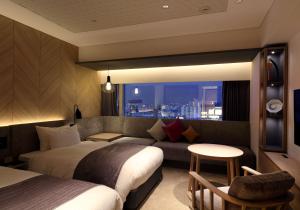 a hotel room with two beds and a couch at Solaria Nishitetsu Hotel Fukuoka in Fukuoka