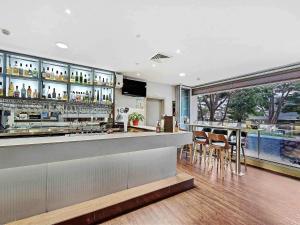 a restaurant with a bar and a large window at Mercure Centro Port Macquarie in Port Macquarie