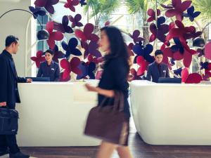 a woman walking in front of a desk with people at Mercure Jakarta Sabang in Jakarta