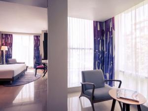 a living room with a bed and a room with a bed and windows at Mercure Jakarta Sabang in Jakarta