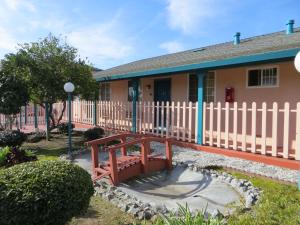 un banco de madera frente a una casa con una valla en Riverside Inn & Suites Santa Cruz, en Santa Cruz