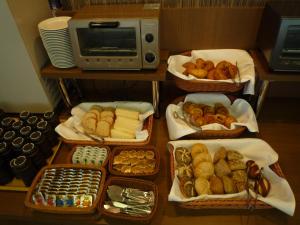 - une table avec plusieurs plateaux de pain et de viennoiseries dans l'établissement Route Inn Grantia Komatsu Airport, à Komatsu