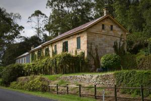 una vieja casa de piedra con una valla delante de ella en Tizzana Winery Bed and Breakfast, en Sackville Reach