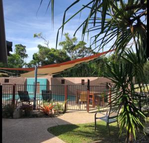 a fence with a bench in front of a pool at Pandanus Holiday Apartments in Mission Beach