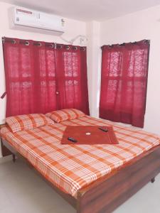 a bed with red curtains and a laptop on it at Sterling Homes Near Sankara Nethralaya & Apollo Hospitals Service Apartments With Kitchen in Chennai