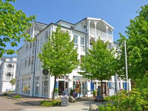 um grande edifício branco com árvores em frente em Seepark Sellin - Apt. 382 em Ostseebad Sellin