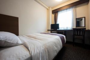 a hotel room with a bed and a desk and a window at Nagasaki Bus Terminal Hotel in Nagasaki