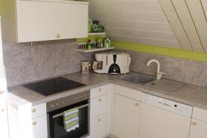 uma cozinha com armários brancos e um lavatório em Ferienwohnung Storchennest em Lohsa