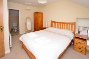 a bedroom with a large white bed and a bathroom at Cottage 236 Roundstone in Roundstone