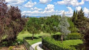 un jardín con un sendero, árboles y una valla en La Villa Del Cedro, en Ciggiano