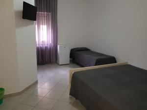 a room with two beds and a tv and a window at Holiday B&B in Vico del Gargano