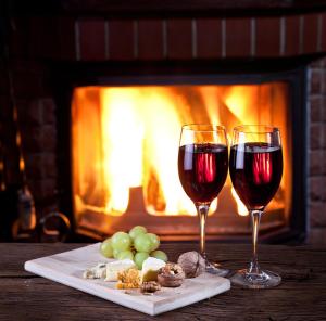 two glasses of red wine and a plate of food in front of a fireplace at Beachside Prevelly Villas in Prevelly