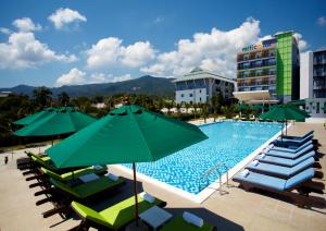 a pool with chairs and umbrellas and a hotel at Samui Verticolor in Chaweng
