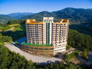 Jiri Mountain Ilsung Condo في Namwon: اطلالة جوية على مبنى كبير فيه جبال في الخلفية