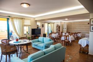 un restaurante con sofás azules, mesas y sillas en Andreolas Luxury Suites, en Tsilivi