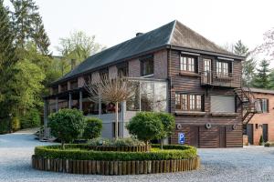 een groot houten huis met een binnenplaats ervoor bij Hostellerie d'Inzepré in Barvaux