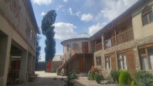 a building with a tree in the middle of a courtyard at Ethno Guest House Caravan Tamchy in Tamchy