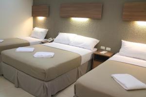 twee bedden in een hotelkamer met handdoeken erop bij The Center Suites in Cebu City