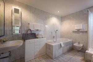 a bathroom with a tub and a sink at Apparthotel Tom Sojer in Ellmau