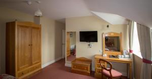 a room with a desk and a mirror and a television at Óstán Oileán Acla in Achill Sound