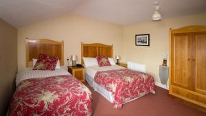 Habitación de hotel con 2 camas y mantas rojas y blancas en Óstán Oileán Acla en Achill Sound