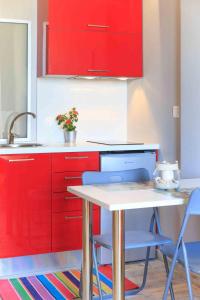 タソスにあるKalliston Beach Apartmentsのキッチン(赤いキャビネット、テーブル、椅子付)