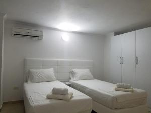 two beds in a room with white walls at Luxury duplex Armand Durres in Golem +51 photos