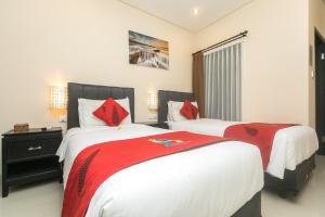 a bedroom with two beds with red and white sheets at Rantun's Place in Nusa Dua