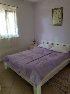 - un lit avec une couette violette dans une chambre dans l'établissement Lily Primosten, à Primošten