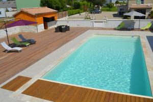 una gran piscina azul en una terraza de madera en Le Coteau de Bazeille Spa & Sauna SAS, en Sainte-Bazeille