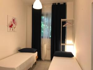 um quarto com duas camas e uma janela com cortinas pretas em Residenza Luna em Paestum