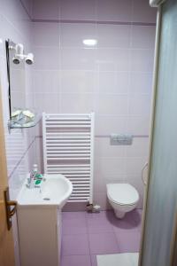 a pink bathroom with a toilet and a sink at Pansion Budimir in Ðakovo