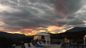 a sunset over a pool with chairs and a gazebo at Luštica Apartments in Luštica