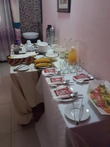 una mesa con platos de comida y vasos. en Sheevy"s Bed N Breakfast en Fort Portal