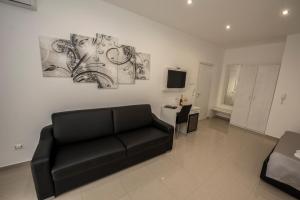 ein Wohnzimmer mit schwarzem Sofa und Fernseher in der Unterkunft La Suite Tropea in Tropea