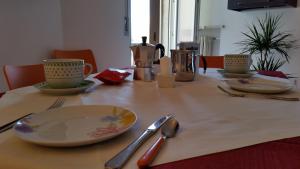a table with plates and utensils on a table at Cabà Holiday Bardolino Gritti in Bardolino