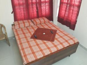 a bed with a laptop on it with red curtains at Sterling Homes Near Apollo/Shankara in Chennai