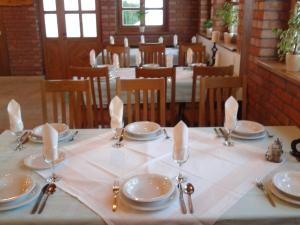 a table with white plates and silverware on a table at Pansion Budimir in Đakovo