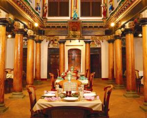 une salle à manger avec une table dans un bâtiment avec des colonnes dans l'établissement ChidambaraVilas, Chettinad - A Luxury Heritage Resort Hotel, Karaikudi, à Kānādukāttān 19 autres photos