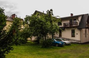 a house with two cars parked in the yard at Gimnazjalna 5 - Apartamenty i pokoje w Centrum Zakopanego in Zakopane