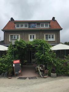 une maison avec une grande haie devant elle dans l'établissement Guesthouse 't Goed Leven, à Stokrooie