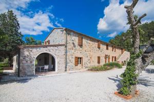 an external view of a stone building with a tree at Villa Cava Alta in Riparbella