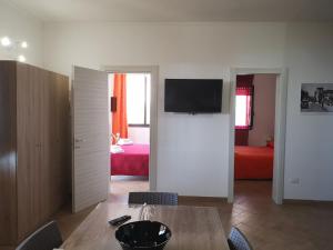 a living room with a table and a television on a wall at Villa Sabbiadoro in Noto Marina