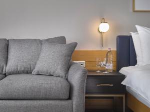 a gray couch sitting next to a bed with wine glasses at K+K Hotel Fenix in Prague