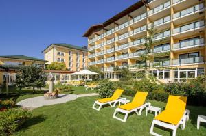 a hotel with yellow chairs and a courtyard at Kurhotel Zink e. K. in Bad Füssing