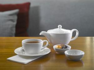 a cup of coffee and a tea pot on a table at K+K Hotel Fenix in Prague