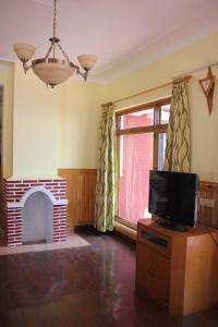 a living room with a tv and a fireplace at Chandruma Cottage in Pauri