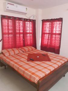 łóżko z czerwonymi zasłonami i laptopem w obiekcie Sterling Homes Near Apollo/Shankara w mieście Ćennaj