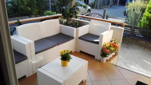 a balcony with white wicker chairs and tables and flowers at Hotel Cesari in Rimini