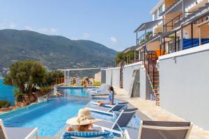 a woman sitting in chairs by a pool at a hotel at Sappho Boutique Suites in Vasiliki